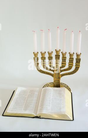 Menorah und offene Bibel mit 7 nicht leuchtende Kerzen auf weißem Hintergrund. Vertikale erschossen. Kopieren Sie Platz. Stockfoto