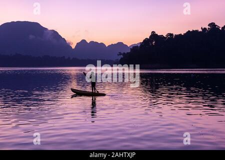 Man stand auf seinem Kajak paddeln an Ratchaprapa Dam, oder als Cheow Lan bekannt, während der Sunrise Dam Stockfoto