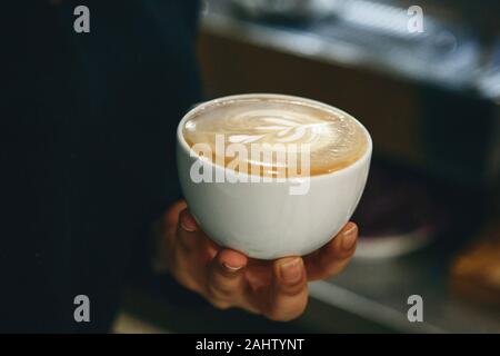 Nahaufnahme eines barista Holding eine Tasse frisch gebrühten Kaffee in der Hand. Stockfoto