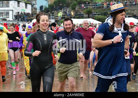 Dorset UK. 01 Jan, 2020. Hunderte von Menschen, die sich der neuen Jahre Tag Schwimmen mit allen die Teilnahme an Fancy Dress am Strand von Lyme Regis in Dorset zu beobachten. Foto: Robert Timoney/Alamy leben Nachrichten Stockfoto