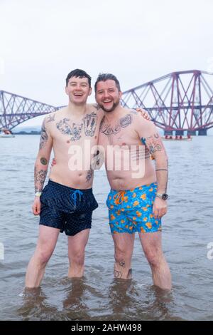 South Queensferry, Edinburgh, Schottland. 1. Jan 2020.. Jecken trotzen der kalten Wasser für den traditionellen Tag der neuen Jahre Loony Dook mit den ikonischen Forth Bridge im Hintergrund Credit: Richard Newton/Alamy leben Nachrichten Stockfoto