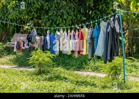Die Wäsche wird auf einem Seil im Garten getrocknet. Trocknen von Kleidung im Hinterhof. Stockfoto
