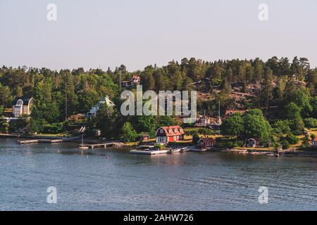 Kleine Hütten in den Stockholmer Schären mit Piers für Ihre kleinen Boote direkt vor Ihnen auf der sonnigen Sommermorgen Stockfoto