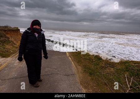 UK, HAPPISBURGH - 18 MAR 2018: Die Frau, die durch die Erosion der Küsten, die während ein Wintersturm. Viele Häuser haben vor kurzem in diesem commun verloren gegangen Stockfoto
