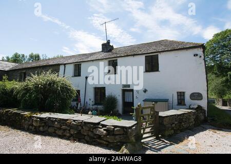 Weißes gestrichenes Haus im Lake District Cumbria altes Cottage Tor Steinwand tv-Antenne auf dem Dach Schieferdach halb abgetrenntes altgeschichtliches Dorf Gebäudetor Stockfoto