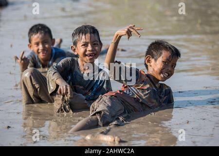 Jereweh, Indonesien - 10. September 2017: Gruppe der Kinder, die Spaß in der Pfütze von Schlamm. Stockfoto