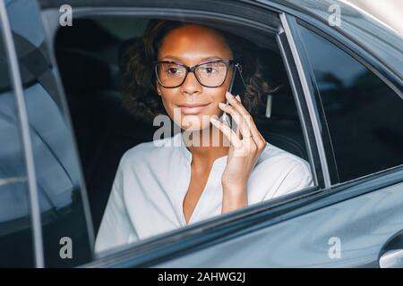 Junge Frau auf dem Handy beim Sitzen auf der Rückbank eines Taxis Stockfoto