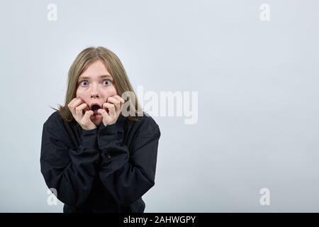 Schockiert junge Frau in der Mode schwarzes Hemd Beißen Nägel, überrascht. Stockfoto