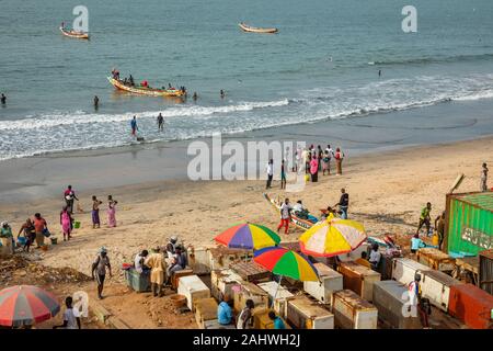 SERREKUNDA GAMBIA - November 21, 2019: Szene mit Männern und Frauen, die Fische aus der Boote am Strand auf Serekunda, Gambia, Westafrika. Stockfoto