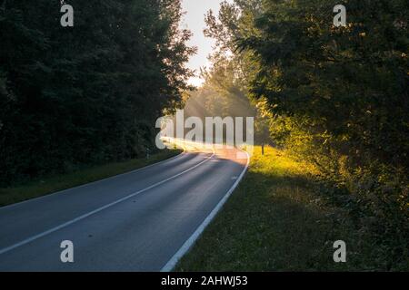 Die Straße, die an der Biegung durch Sonnenlicht beleuchtet wird. Sie vertreten die Inspiration, Gottes Erscheinungen, Aufklärung Stockfoto