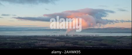 Panorama auf das Meer, auf die Bucht gibt es einen großen Ölraffinerie. Rauch steigt aus der Schornsteine, die Mixe mit einer riesigen Wolke, geheiligt durch Sonnenuntergang lig Stockfoto