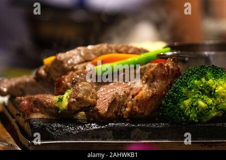 Close up Rindfleisch auf heiße Teller auf Feuer mit Gemüse. Live Cooking im Restaurant. Stockfoto