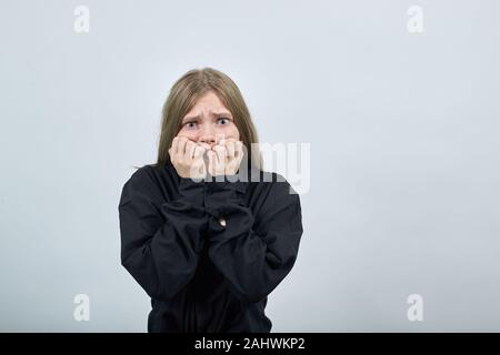 Angst junge Frau in der Mode schwarzes Hemd Beißen Nägel, überrascht. Stockfoto