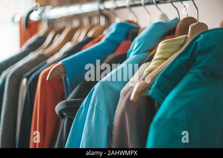 Verschiedene Kleidung auf dem Stand auf dem Kleiderbügel im Schrank Stockfoto