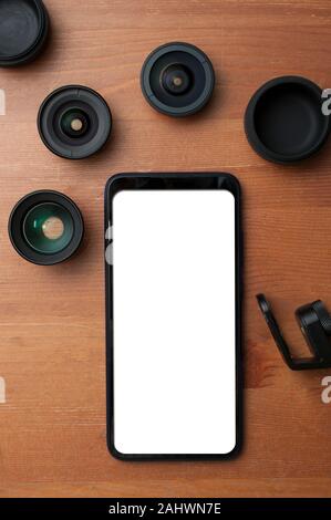 Leerer Bildschirm Smartphone auf Holztisch mit einigen Add-on Linsen Stockfoto