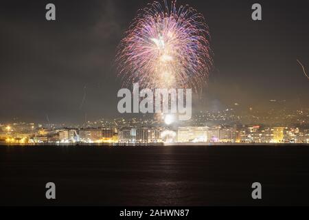 Serie von Feuerwerk über den großen Wohngebiet Landschaft bei Nacht. Silvester Feuerwerk in Thessaloniki, Griechenland aus der Stadt am Wasser gesehen. Stockfoto