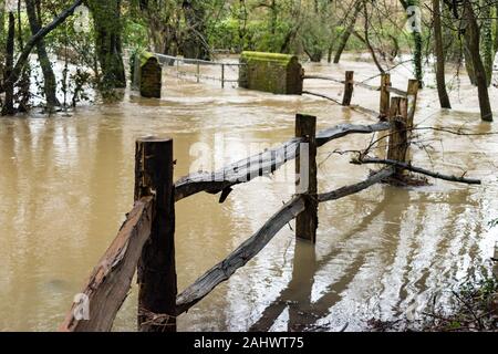 Ein Zaun führt zu einer Fußgängerbrücke wird Teil des Flusses Maulwurf in Brockham, Surrey, UK, als Schwere Regenfälle verursachten Überschwemmungen in Surrey und Sussex im Dez 2019 Stockfoto