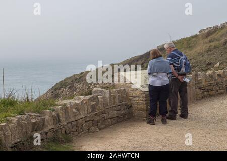 Zwei Wanderer Lesen der Zeichen über Tilly Laune Höhlen in Durlston Country Park, Swanage, Dorset, Großbritannien Stockfoto