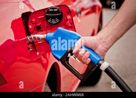 Horizontale Schuß eines Menschen Hand Benzin pumpen in ein rotes Auto. Stockfoto