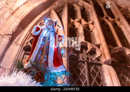 Vater Weihnachtskugel saß oben auf der einen Weihnachtsbaum mit einem großen Kathedrale im Hintergrund das Fenster. Stockfoto