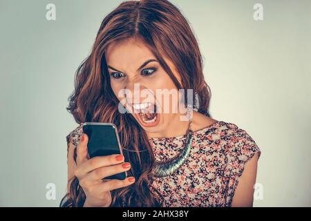 Frau schreiend in Rage suchen am Telefon Empfangen oder Senden einer sehr schlechten Gesang oder viseo Nachricht. Mixed Race Modell auf der hellgrünen Hintergrund w isoliert Stockfoto