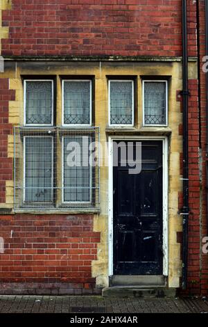 Schwarze Tür auf alten roten Backsteinhaus mit über Windows gated Stockfoto