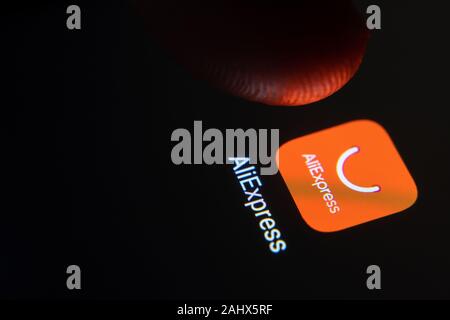 AliExpress App-Symbol auf dem Smartphone-Bildschirm und Finger starten Sie es. Stockfoto