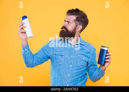 Die Behandlung mit individueller Betreuung. Hipster halten Haar Shampoo und Conditioner gelben Hintergrund. Haar Behandlung. Shampoonieren und Klimaanlage. Bart Behandlung Produkte. Haut Behandlung. Hautpflege. Stockfoto