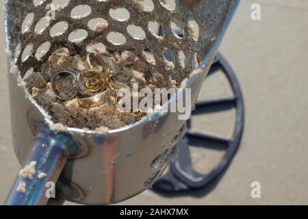 Schmuck in Strand sand Schaufeln mit Metalldetektorspule auf Sand im Hintergrund am Strand in Florida. Stockfoto