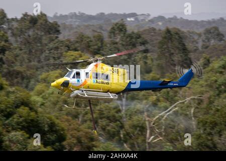 Bell 412 Hubschrauber, die nach dem Befüllen mit einer Belastung von Wasser ein Feuer zu bekämpfen. Stockfoto