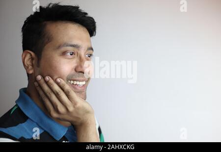 Rechts ein nettes Gesicht eines asiatischen Mann mit der Hand am Kinn lächelnd, Gefühl, froh und mit Blick auf eine Kopie Raum mit weißem Hintergrund Stockfoto