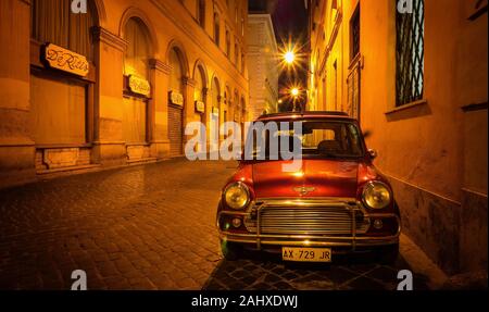 Rom, Italien, 18. Juni 2014. Eine rote Britische Mini Auto an der Seite eines traditionellen gepflasterten Straße geparkten spät in der Nacht, unter Amber Street. Stockfoto