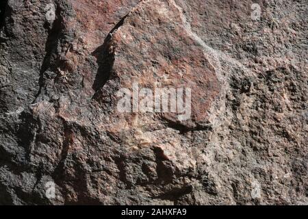 Nahaufnahme von einem großen Stein in rot, orange und schwarzen Farbtönen. Auf diesem Foto sehen Sie die rustikale Textur einer Rock im Detail. Perfektes Hintergrundbild. Stockfoto