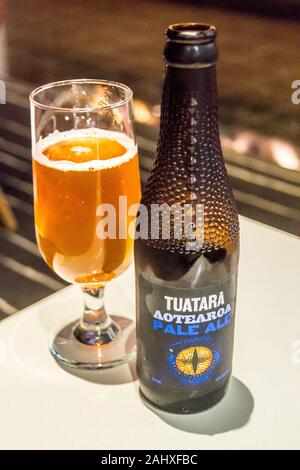 FOTOGRAFIEREN Sie EIN Glas und eine Flasche Tuatara Aotearoa Pale Ale in einer geformten Flasche, Qantas International Business Lounge, Auckland Airport, Neuseeland Stockfoto