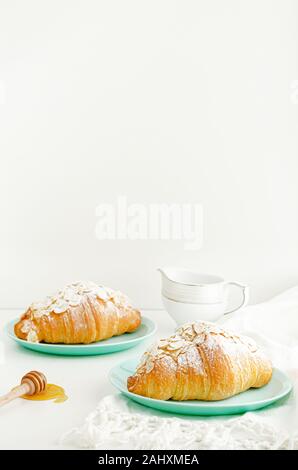 Croissants mit mandelflocken und Puderzucker auf Türkis Platte. Kopieren Sie Raum, senkrecht. Frühstück Konzept Stockfoto