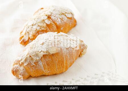 Frühstück Bäckerei, Croissant mit Puderzucker und Mandelflocken auf weißem Hintergrund. Close Up. Stockfoto