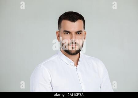 Ruhe gut aussehender bärtiger Mann posiert im Studio auf grauem Hintergrund Stockfoto