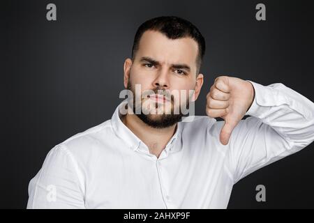 Portrait von Happy bärtiger Mann mit Daumen unten auf schwarzen Hintergrund. Stockfoto