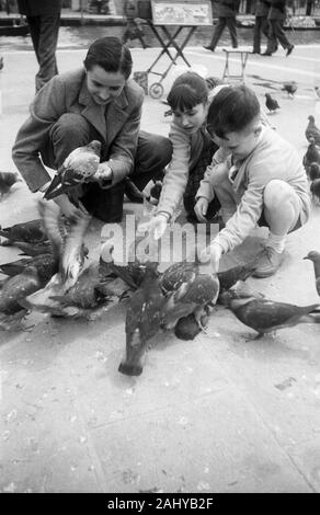 Kinder beim Füttern Tauben auf dem Markusplatz in Venedig, Italien 1954. Kinder füttern Tauben auf dem Markusplatz in Venedig, Italien 1954. Stockfoto