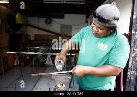 Antipolo City, Philippinen - Dezember 27, 2019: Arbeitnehmer in einem Stahlbau shop Schleifen und Glätten, eine Stange aus Stahl. Stockfoto