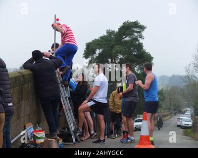 Mappleton (oder Mapleton) Brücke springen, jährlichen Tag der neuen Jahre Benutzerdefiniert. Teilnehmer gekleidet, wie Wo ist Wally aus springt Okeover Brücke und in Fluss Dove. Stockfoto