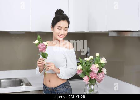 Junge asiatische Frau Anordnen von Blumen in der Küche. Stockfoto