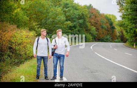 Gehen müssen. wanderlust Konzept. Wandern mit Freunden ist cool. gegangen, sich selbst zu finden. Reise trampen. Zwillinge zu Fuß entlang der Straße. Trampen auf leere Straße. Anreise per Trampen. Road Trip. Stockfoto