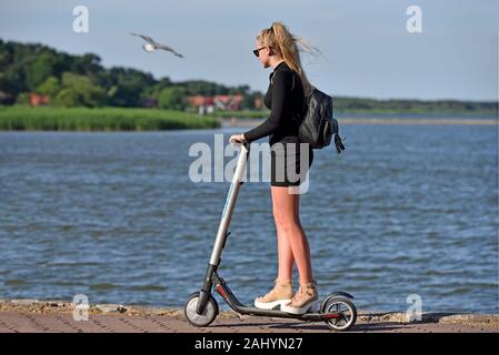 Junge Frau reiten Roller auf der Strandpromenade in Nida, Kurische Nehrung, Litauen, Baltikum, in Nord Europa.