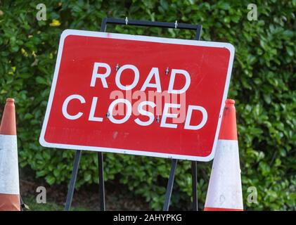 Eine rote Straße Schliessen Zeichen (UK) in der Mitte der roten und weißen Leitkegel. Stockfoto