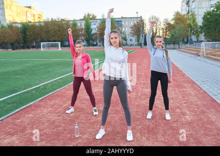 Positive Frauen Sport Übungen.. Die Gruppe der drei schöne junge Frauen, die Sport im sonnigen Tag im Park. Stockfoto