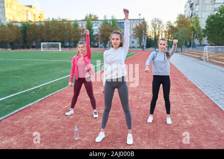 Positive Frauen Sport Übungen.. Die Gruppe der drei schöne junge Frauen, die Sport im sonnigen Tag im Park. Stockfoto