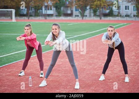 Positive Frauen Sport Übungen.. Die Gruppe der drei schöne junge Frauen, die Sport im sonnigen Tag im Park. Stockfoto