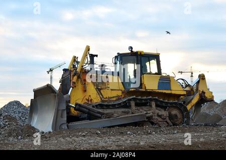 Anschluss - Typ Bulldozer auf der Baustelle. Flurbereinigung, Sortierung, Pool, Aushub, Grabenaushub und Fundament graben während der Großen konstruieren Stockfoto