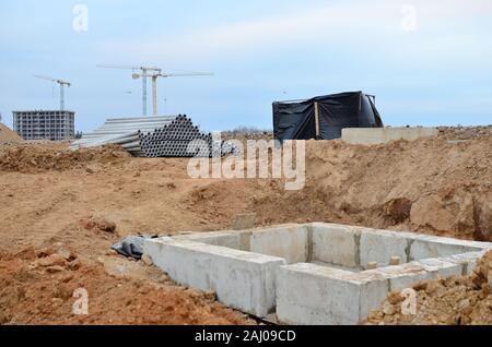 Installation von konkreten Abwasserkanal Vertiefungen im Boden auf der Baustelle. Die Verwendung von Stahlbeton Ringe für Senkgruben, Überlauf Klärgruben Stockfoto